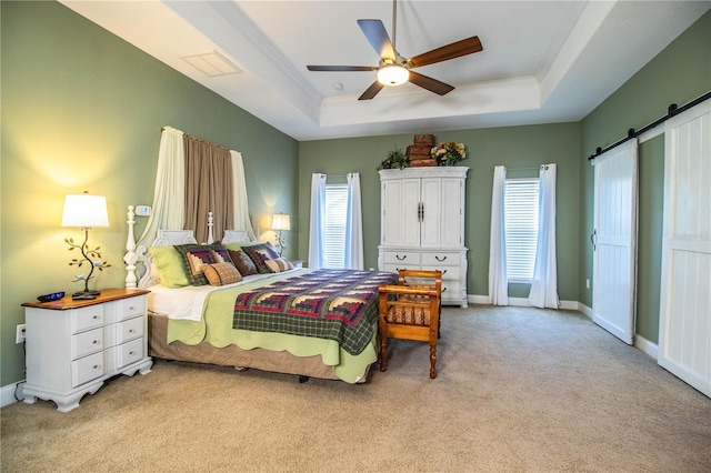 bedroom with crown molding, baseboards, a barn door, light carpet, and a raised ceiling