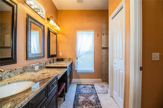 bathroom featuring double vanity, visible vents, baseboards, and a sink