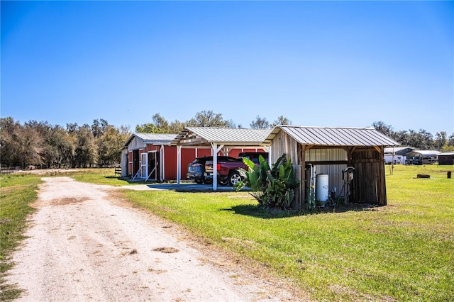 view of pole building with a carport, driveway, and a yard