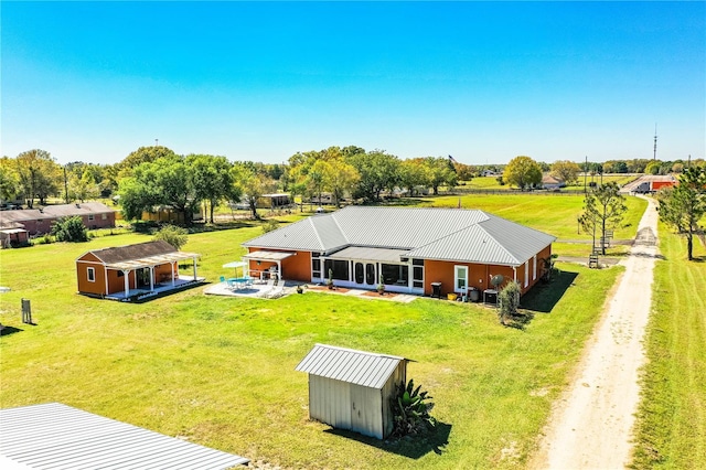 back of house featuring metal roof, a lawn, an outdoor structure, and dirt driveway