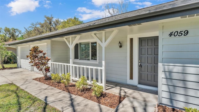 entrance to property featuring a porch, a garage, and driveway