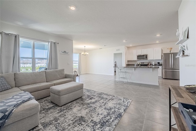 living area with baseboards, a chandelier, light tile patterned floors, recessed lighting, and a textured ceiling