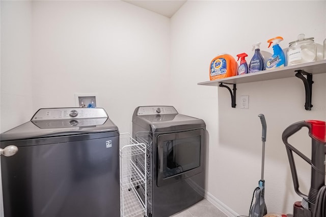 clothes washing area with washing machine and clothes dryer, laundry area, tile patterned floors, and baseboards