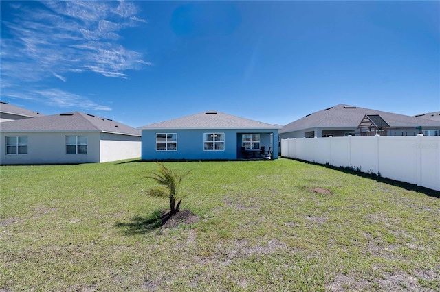 back of property with stucco siding, a lawn, and fence