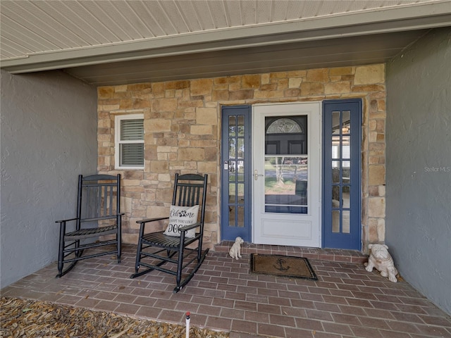 view of exterior entry with stone siding and stucco siding