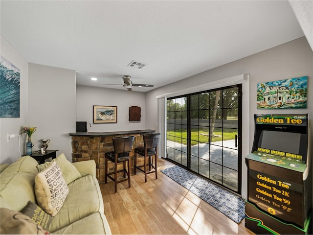 interior space with ceiling fan, visible vents, wood finished floors, and a dry bar