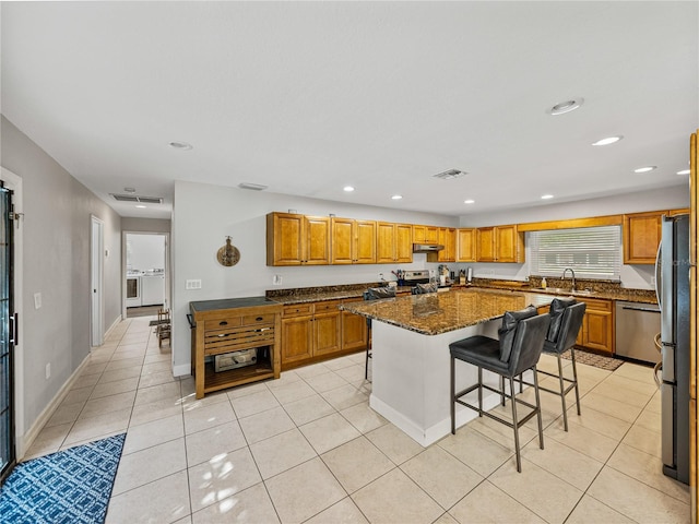 kitchen with visible vents, under cabinet range hood, light tile patterned floors, appliances with stainless steel finishes, and a sink