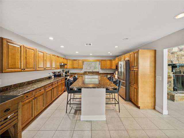 kitchen featuring visible vents, a breakfast bar, a center island, stainless steel appliances, and light tile patterned floors