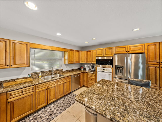 kitchen with light tile patterned floors, recessed lighting, brown cabinets, stainless steel appliances, and a sink