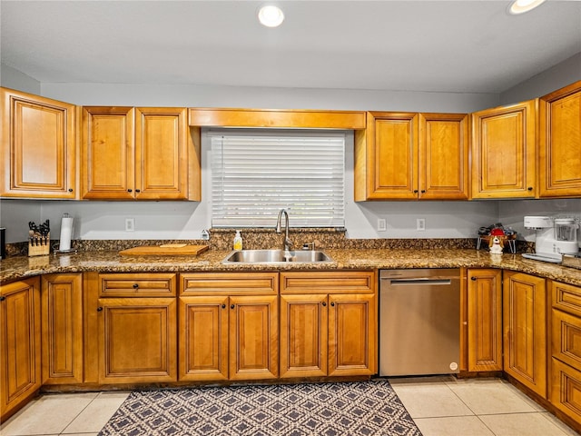 kitchen featuring dishwasher, light tile patterned floors, brown cabinetry, and a sink