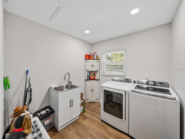 clothes washing area with light wood-type flooring, washer and clothes dryer, a sink, recessed lighting, and cabinet space