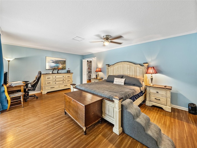 bedroom with a textured ceiling, crown molding, baseboards, and wood finished floors