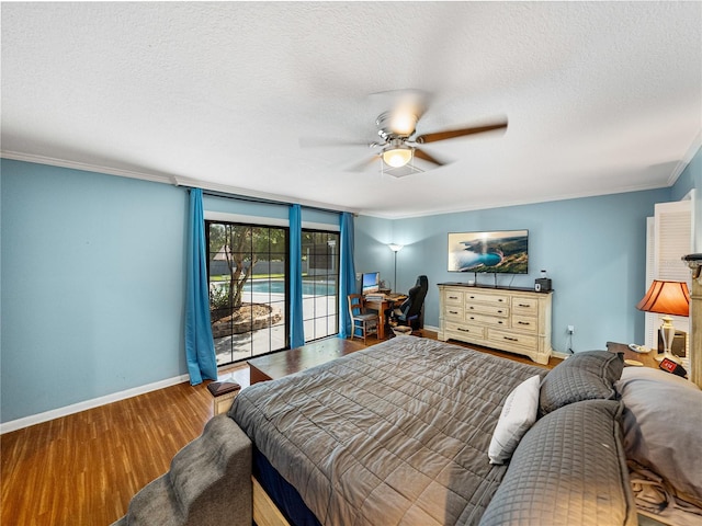 bedroom featuring a textured ceiling, wood finished floors, baseboards, and ornamental molding