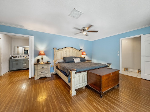 bedroom featuring visible vents, baseboards, hardwood / wood-style floors, and ornamental molding