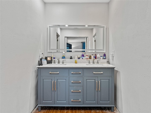 bathroom with double vanity, wood finished floors, and a sink