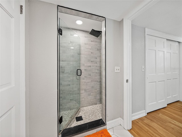 full bath featuring a stall shower, baseboards, and wood finished floors