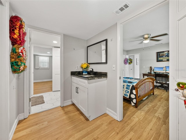 kitchen featuring dark countertops, light wood-style floors, visible vents, and a sink