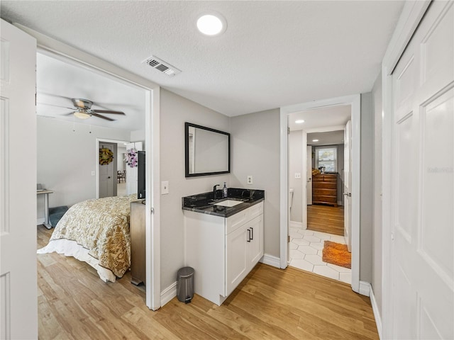 interior space featuring a sink, visible vents, a textured ceiling, and light wood-style flooring