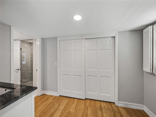 interior space with light wood-style flooring, baseboards, a closet, and a textured ceiling