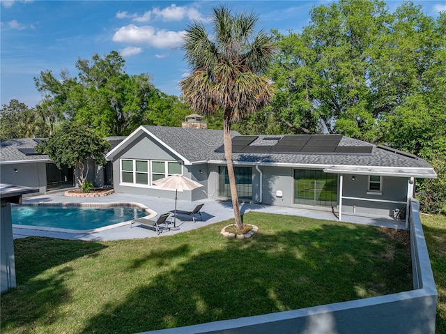 back of property featuring solar panels, a shingled roof, a lawn, a patio area, and an outdoor pool