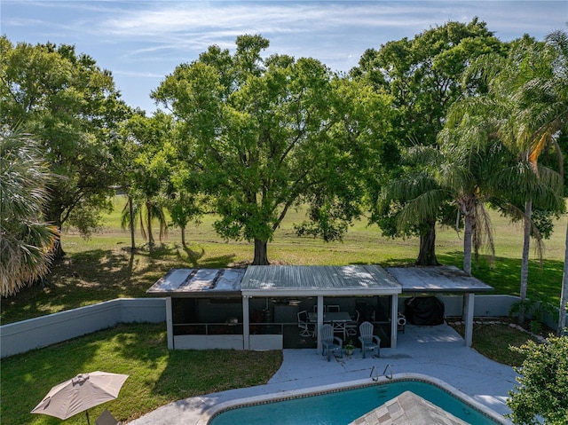 view of swimming pool featuring a yard, a patio, a fenced in pool, and a sunroom