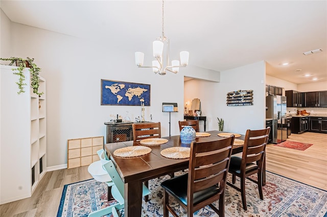 dining room with a chandelier, visible vents, light wood-type flooring, and baseboards