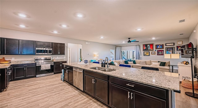 kitchen featuring a ceiling fan, light wood-style flooring, a sink, appliances with stainless steel finishes, and open floor plan