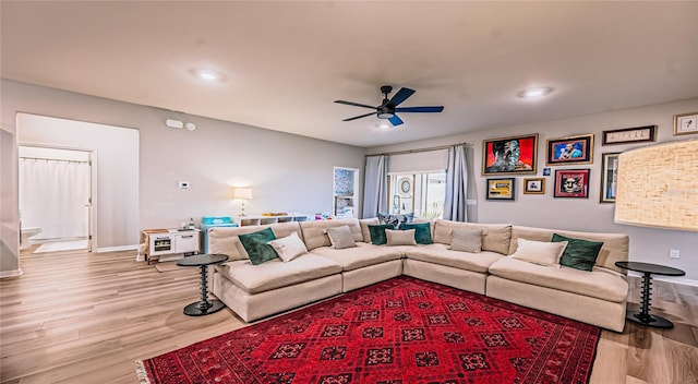 living area with light wood-type flooring, baseboards, and a ceiling fan