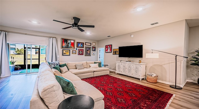 living area featuring a ceiling fan, wood finished floors, visible vents, and baseboards