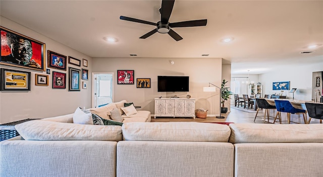 living room featuring wood finished floors, recessed lighting, ceiling fan with notable chandelier, and visible vents