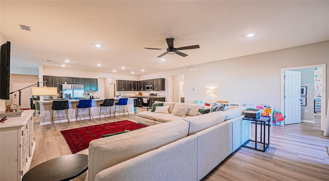 living room with recessed lighting, visible vents, light wood-style flooring, and a ceiling fan