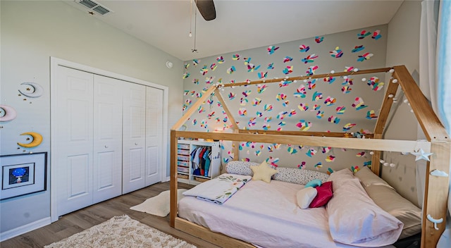 bedroom with ceiling fan, visible vents, a closet, and wood finished floors