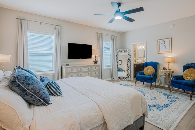 bedroom featuring ceiling fan, baseboards, ensuite bath, and wood finished floors