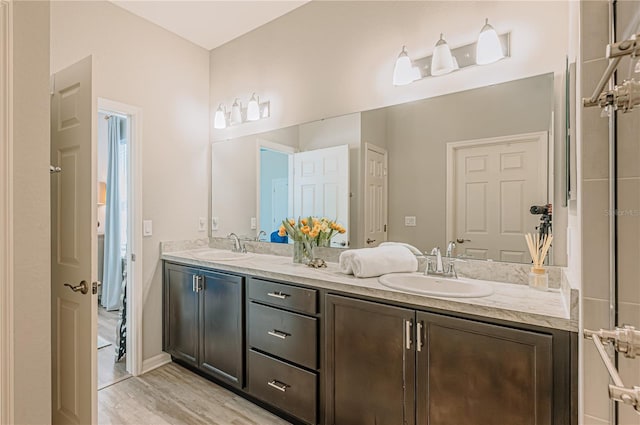 full bath with double vanity, wood finished floors, and a sink