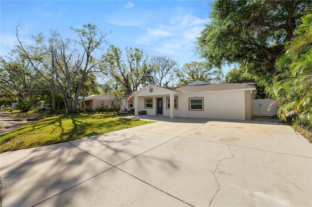 view of front of home featuring a front yard, a gate, fence, driveway, and stucco siding