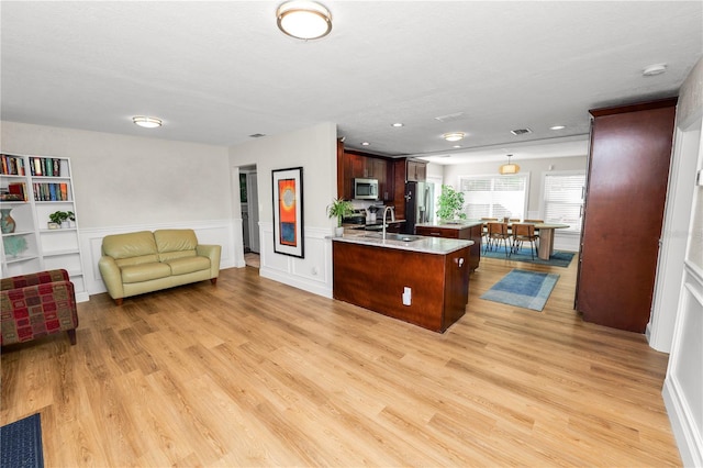 kitchen with a peninsula, a sink, light countertops, appliances with stainless steel finishes, and open floor plan