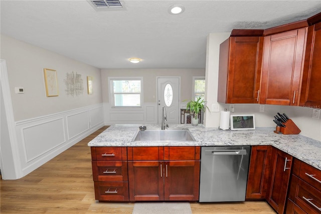 kitchen featuring light stone countertops, visible vents, a peninsula, a sink, and stainless steel dishwasher