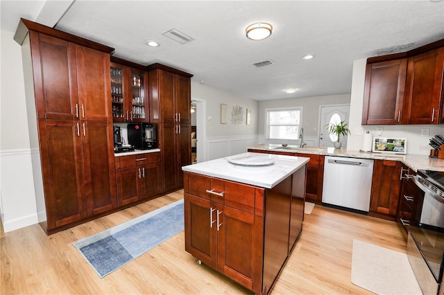 kitchen featuring a sink, visible vents, light wood-type flooring, and stainless steel dishwasher