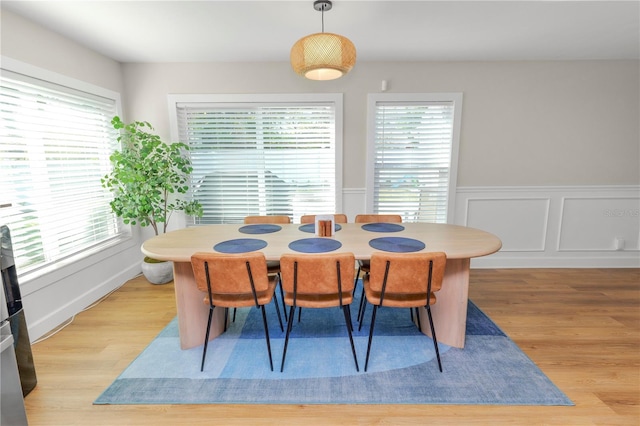 dining room featuring a decorative wall, light wood-style floors, and a wainscoted wall