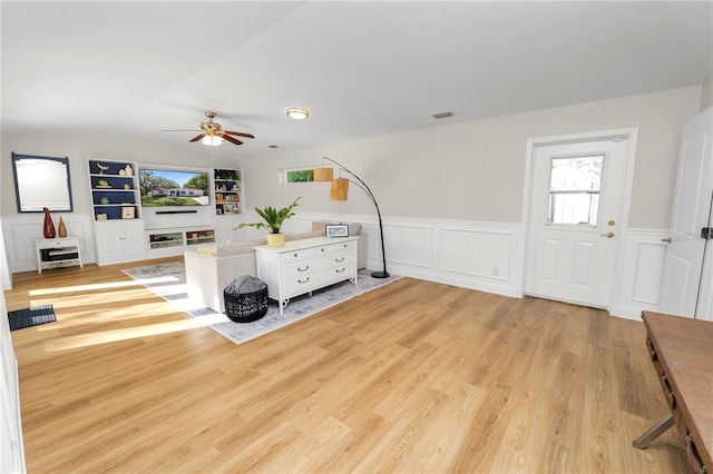 living area featuring built in features, lofted ceiling, visible vents, and wood finished floors