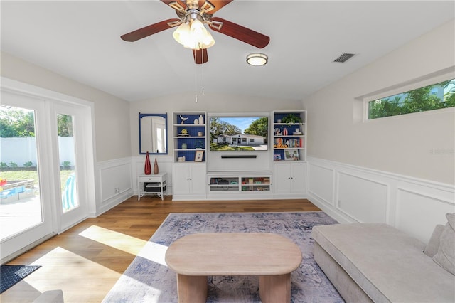 living room with a wealth of natural light, visible vents, lofted ceiling, and light wood finished floors