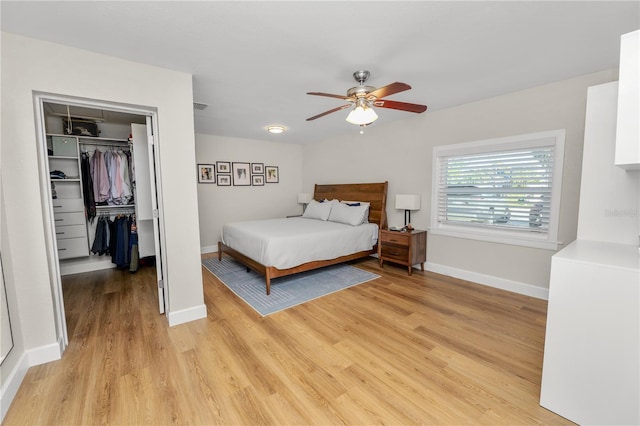 bedroom featuring a closet, baseboards, light wood-style flooring, and a spacious closet