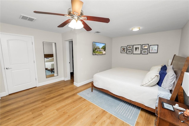 bedroom featuring ceiling fan, visible vents, baseboards, and light wood-style flooring