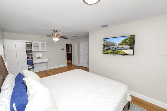 bedroom featuring ceiling fan, baseboards, visible vents, and light wood-type flooring