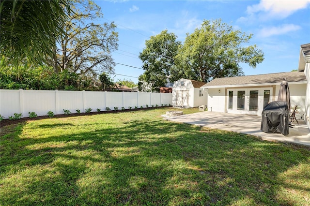 view of yard with an outdoor structure, a fenced backyard, a shed, and a patio area