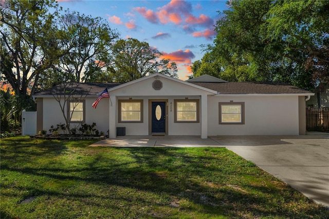 ranch-style home featuring stucco siding, a lawn, and fence