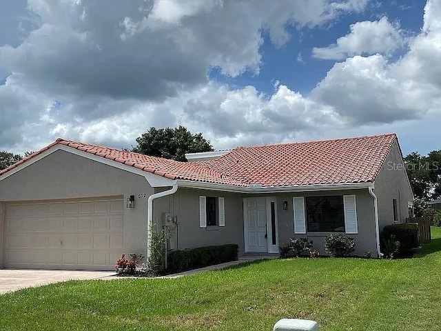 view of front of house featuring stucco siding, driveway, a front lawn, a tile roof, and a garage