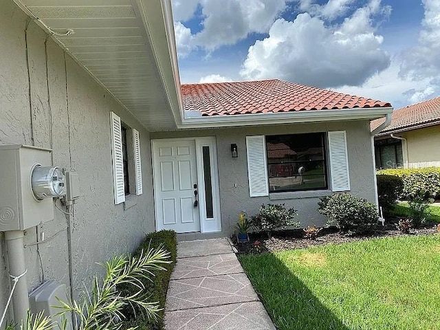 view of exterior entry with stucco siding and a tiled roof