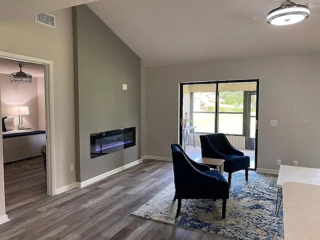 living area with visible vents, baseboards, lofted ceiling, and wood finished floors