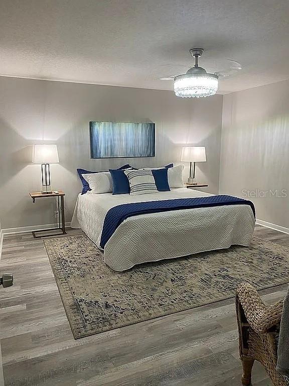 bedroom featuring a textured ceiling, baseboards, and wood finished floors